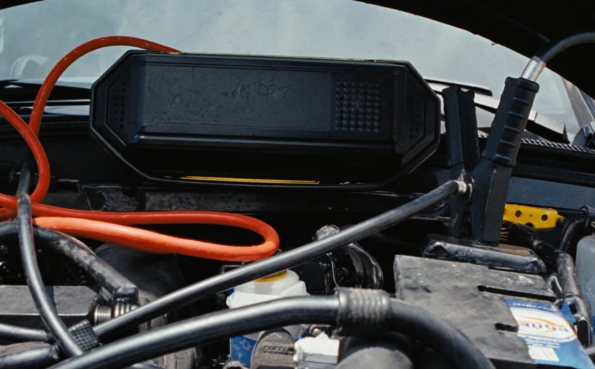 Jumper cables clamped to a car battery under an open hood