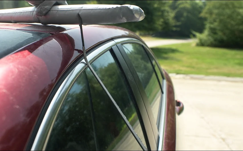 A lockout tool worked into the top corner of a car door frame