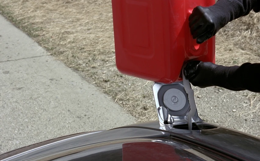 A fuel can being emptied into the filler neck of a car at the roadside