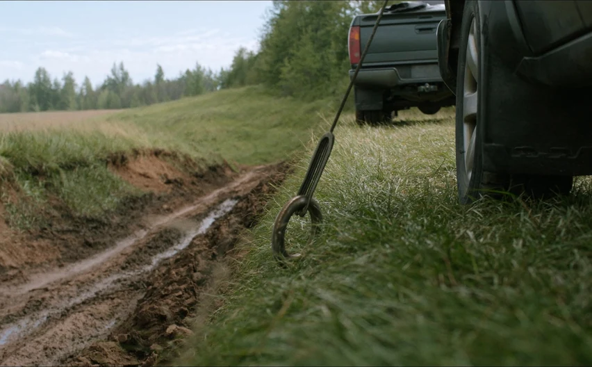 A winch cable running to a truck stuck in a muddy ditch